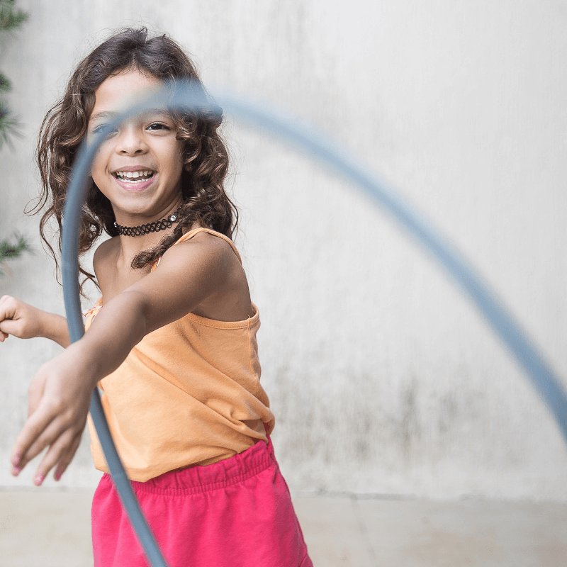 Preschool girl playing with hula hoop