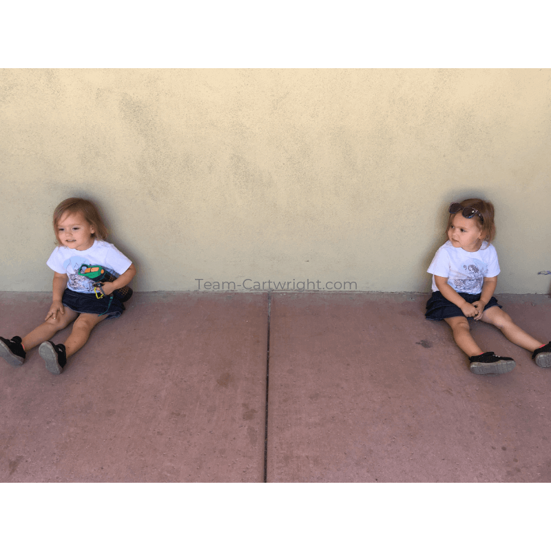 picture of twins sitting a few feet apart against a wall