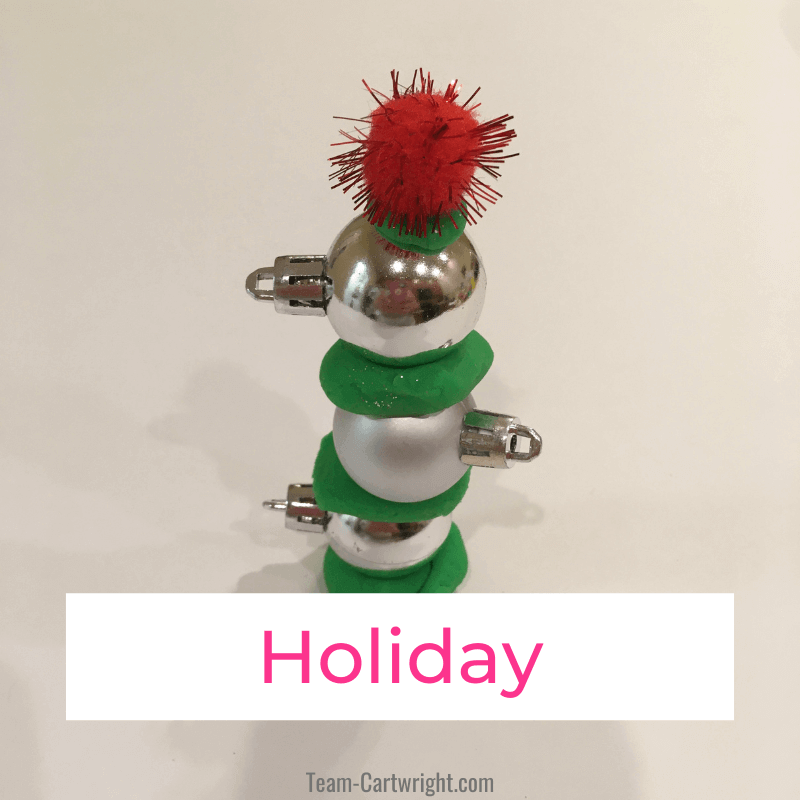 Link to: Holiday Activities for Kids Text: Holiday  Picture: small ornaments stacked into a tree with green playdough and red puff ball for christmas tree engineering challenge