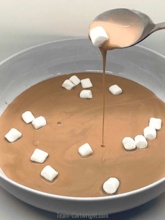 picture of hot chocolate oobleck falling out of a spoon with marshmallows