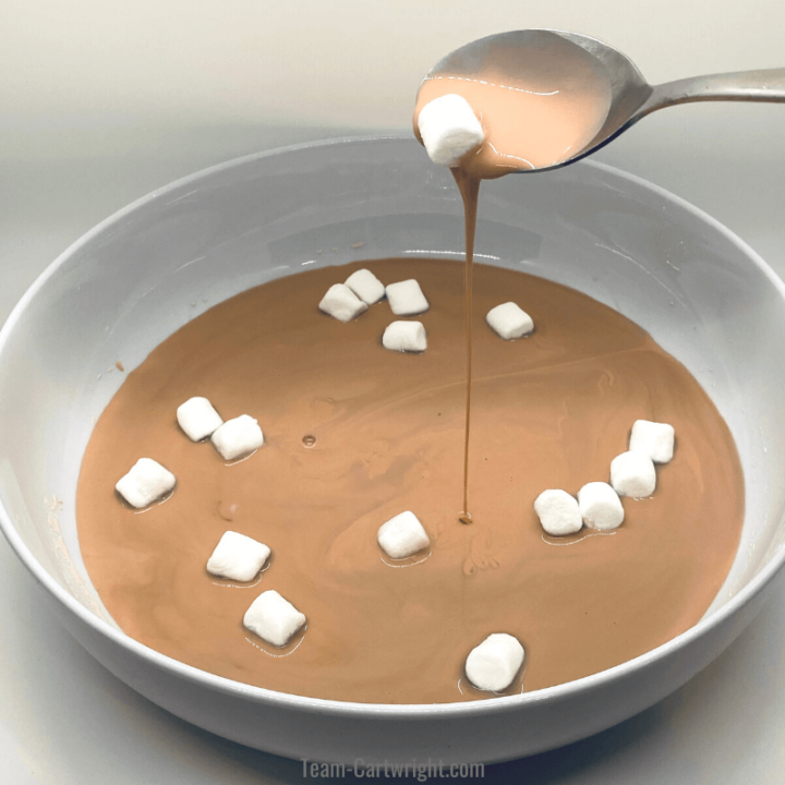 picture of hot chocolate oobleck falling out of a spoon with marshmallows