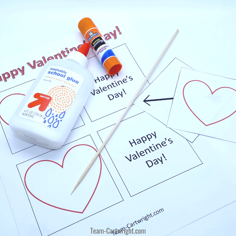 picture of free printable thaumatrope valentines, skewer for making them, liquid glue, and a glue stick