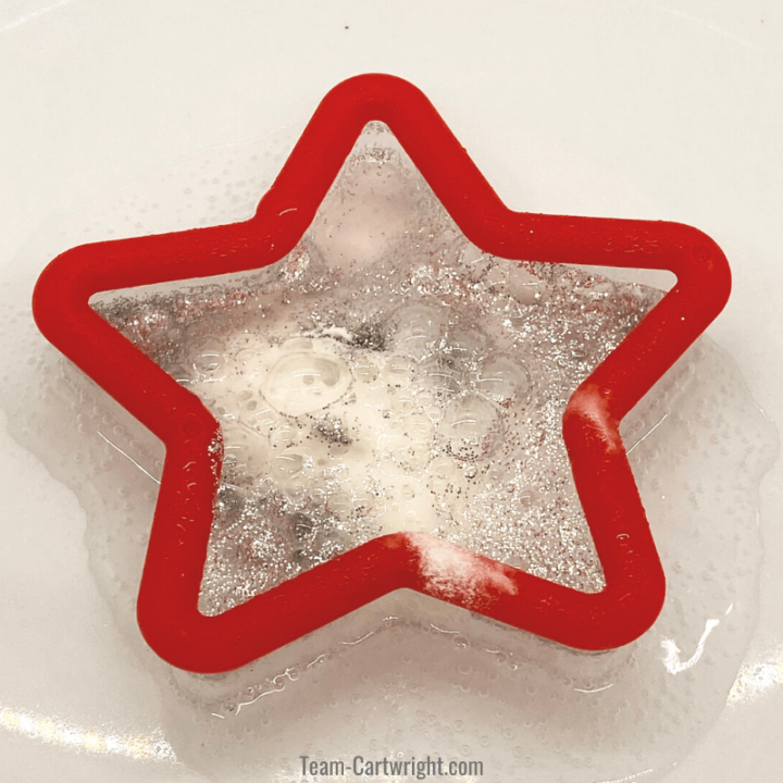 picture: red star cookie cutter with chemical reaction bubbling and bringing glitter to the surface