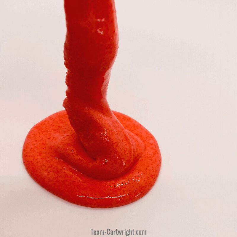 red slime being played with, oozing down to a pile
