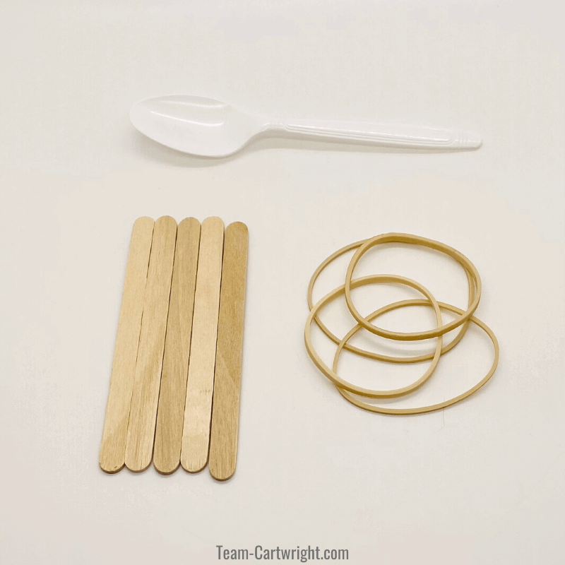 supplies for popsicle stick catapult including 5 craft sticks, a plastic spoon. and rubber bands